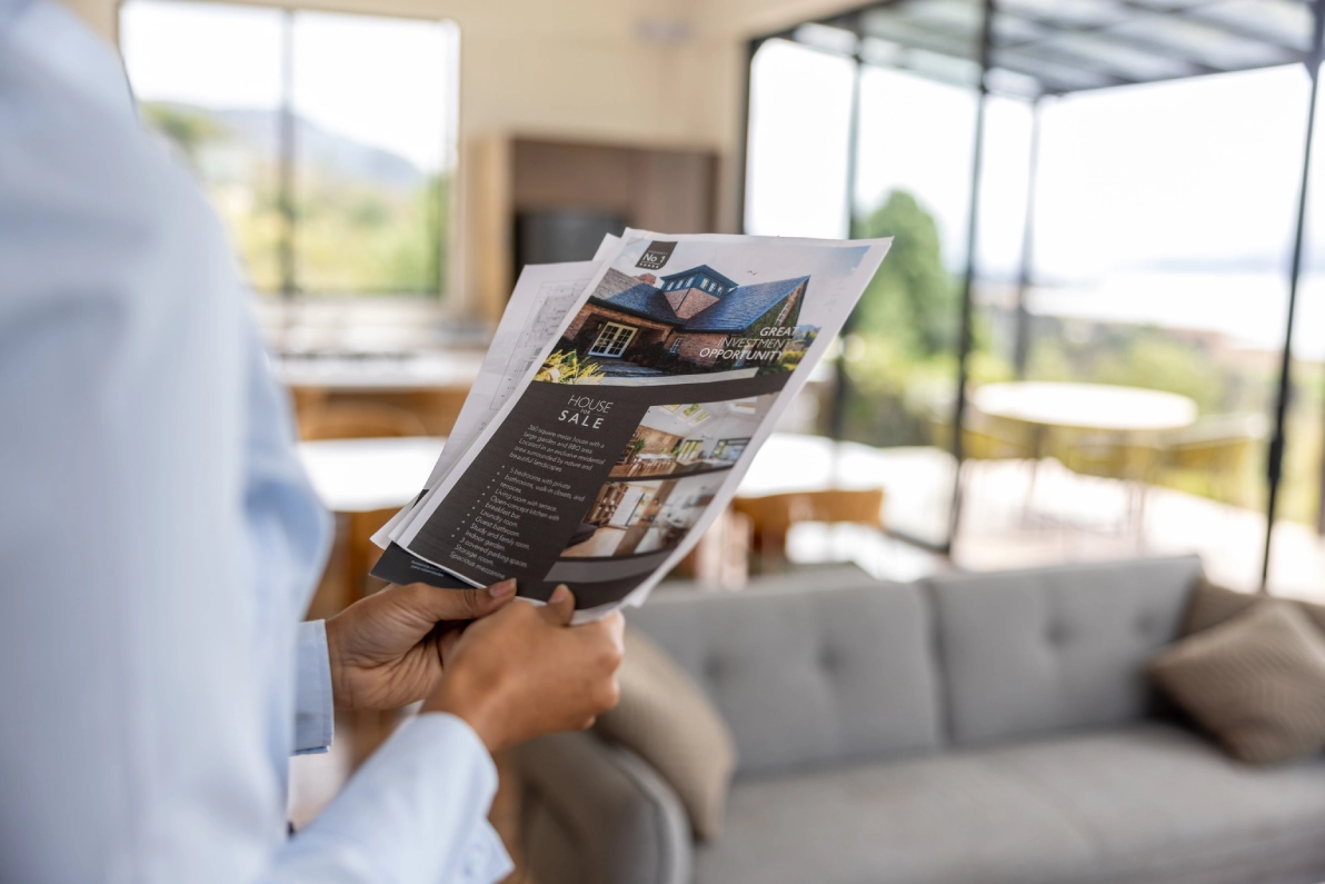 Person holding real estate brochures indoors